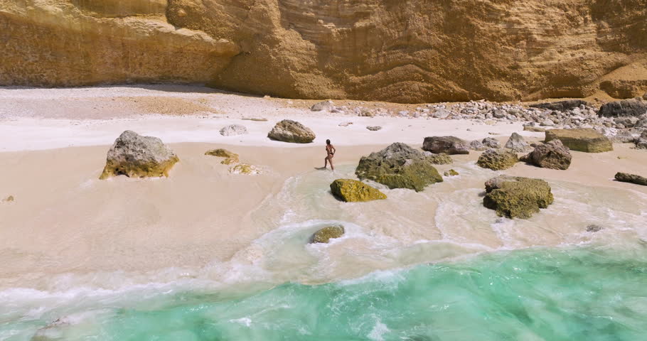 Woman Walking And Running On The Beach With Waves Crashing On The Rocks In Summer In Socotra Island, Yemen. - aerial shot