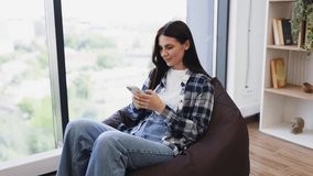 Young Caucasian woman smiling while using a smartphone, relaxed atmosphere at home - Powered by Shutterstock - Get 15% off with code: PIKWIZARD15
