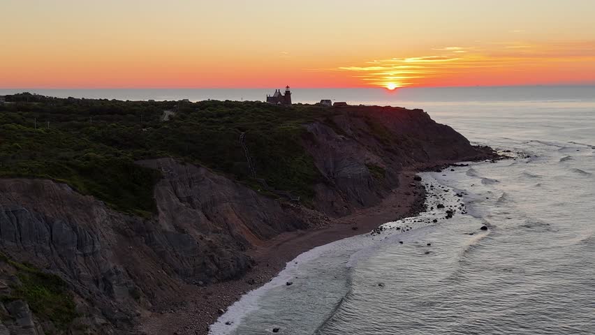 Aerial view of the striking Mohegan Bluffs meeting the ocean as the sun sets in a blaze of color, New Shoreham, Rhode Island, United States.