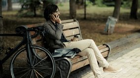 Man Talking On Smartphone While Sitting On Park Bench. Freelancer Taking Business Call. Modern Urban Lifestyle And Remote Work. Bike Ride Commute, Outdoors Communication. Urban Cyclist Digital Nomad - Powered by Shutterstock - Get 15% off with code: PIKWIZARD15