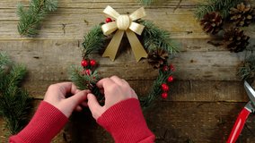 Making Christmas wreath using spruce twigs, golden bow and red berries. Woman creating winter season home decoration. - Powered by Shutterstock - Get 15% off with code: PIKWIZARD15