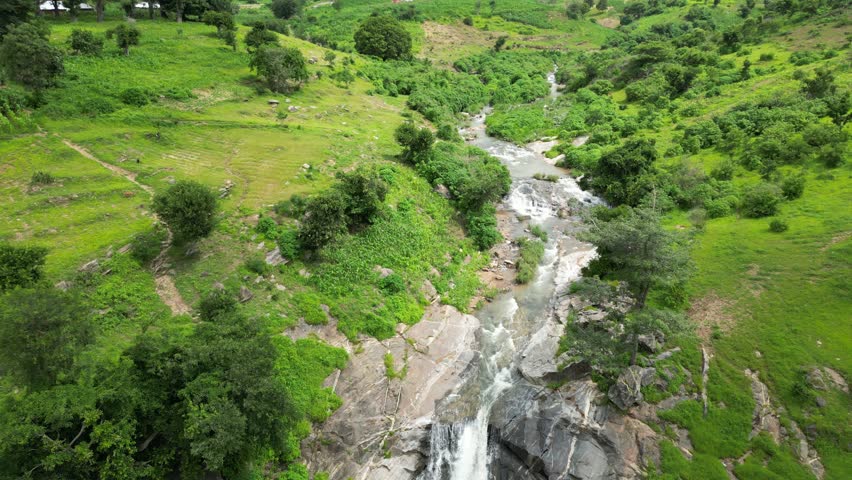 Aerial view of a tiered waterfall cascading through lush green vegetation and rocky terrain, creating a picturesque and scenic landscape, Mazah Village, Plateau, Nigeria.
