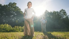 Boy jumps ahead in racing game. Children play on green grass outdoor. Happy summer fun. Girl follows playful boy. Racing brings jumping joy. Outdoor grass scene with happy children. Playful summer joy - Powered by Shutterstock - Get 15% off with code: PIKWIZARD15