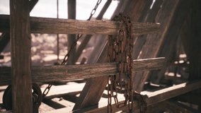 Rusty chains hang loosely over weathered wooden beams at an old construction site, exposed to sunlight and surrounded by a barren landscape, evoking feelings of abandonment and neglect. - Powered by Shutterstock - Get 15% off with code: PIKWIZARD15