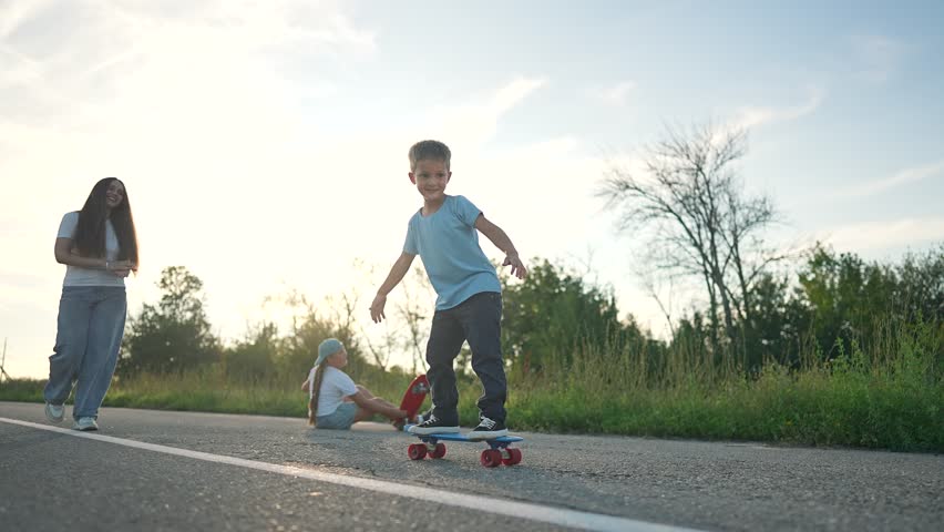 The boy rides his skateboard with a big smile, enjoying every moment. The outdoor environment gives the boy a sense of freedom. The skateboard rolls smoothly down the road, making his ride exciting.