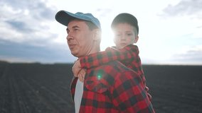 Father gives piggyback ride son. Outdoor sunset field bright. Happy son smiles piggyback. Father child walk on field. Piggyback fun bond father child. Son happy outdoors with father bond strong. - Powered by Shutterstock - Get 15% off with code: PIKWIZARD15