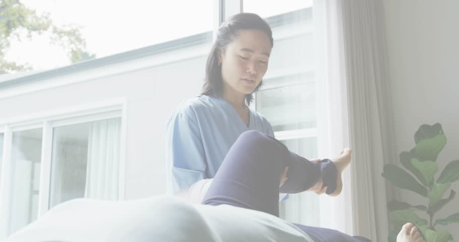 Therapist lifting client's leg for knee-chest stretch, overlay scrolling years glitching lines. Rehabilitation, physiotherapy, digital interface, wellness, therapeutic, movement, healthcare