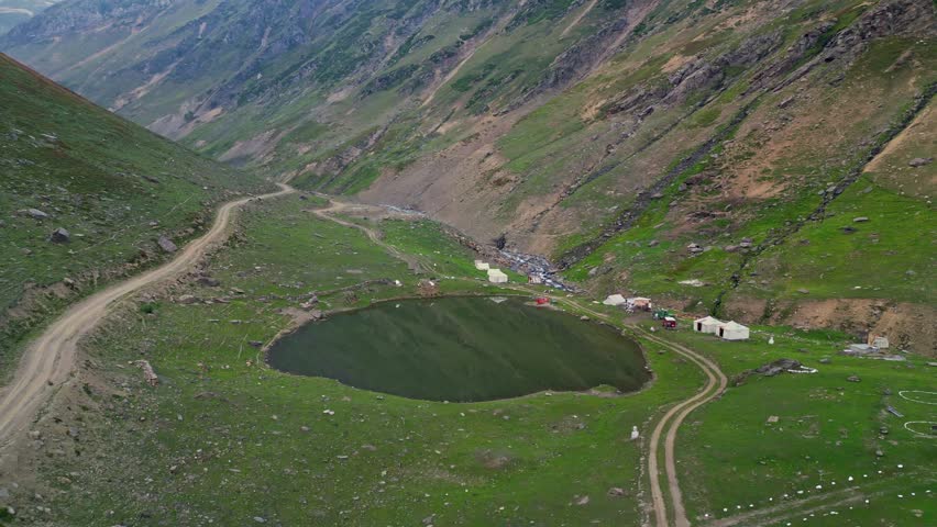 High-Altitude Tent Camp in Scenic Mountain Valley at Sunrise, Surrounded by Rolling Hills and Rugged Terrain — Remote Travel Destination for Nature and Adventure Enthusiasts