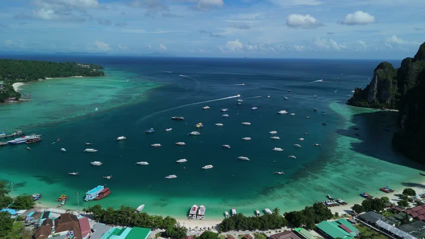 Drone pans right across Loh Dalum Beach, boats, and turquoise bay on Phi Phi Don