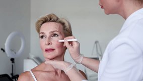 Closeup of mature woman with face contour lines during anti-aging consultation at beauty clinic. Dermatologist preparing for cosmetic facelift procedure. Skincare, rejuvenation and aesthetic treatment - Powered by Shutterstock - Get 15% off with code: PIKWIZARD15