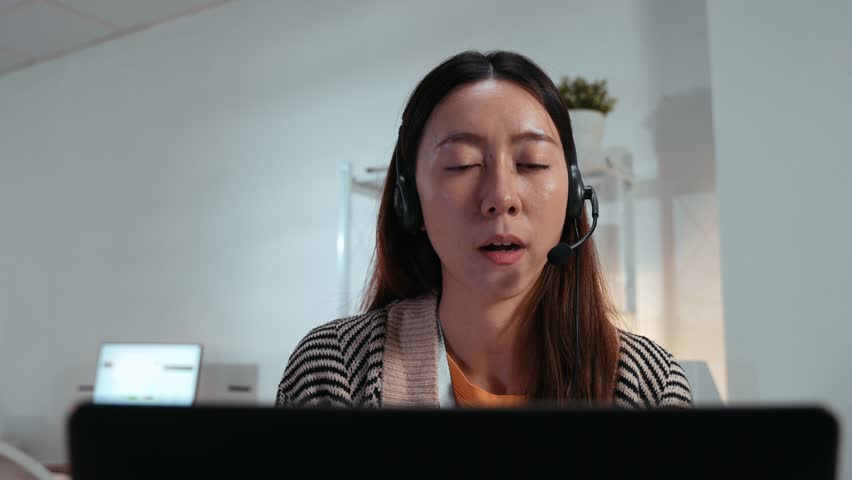Asian female call center with headset talking or online meeting with client. Presenting project, customer service, IT support. Communication, teleworking, and video conferencing in a remote work