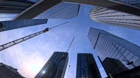 Modern city skyscrapers reflect blue sky and sun while construction cranes signal urban development and economic growth in a contemporary financial district skyline - Powered by Shutterstock - Get 15% off with code: PIKWIZARD15