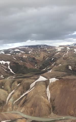 Vertical cinematic aerial helicopter flyover of colorful Landmannalaugar mountains in the Icelandic highlands on a summer day.