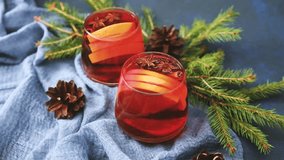 Two mulled wine drinks with orange slices and star anise, surrounded by pine branches and pinecones. - Powered by Shutterstock - Get 15% off with code: PIKWIZARD15