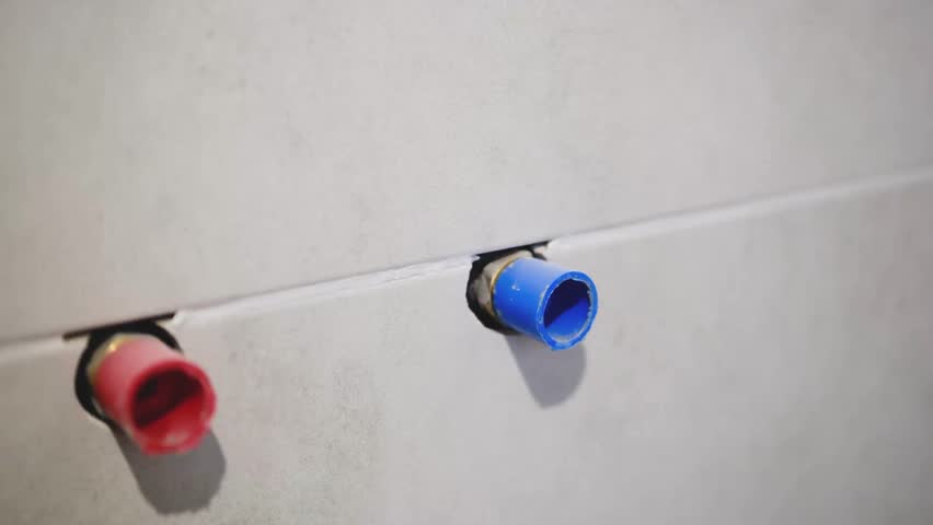 Red and blue pipe ends in wall detail for plumbing and construction projects