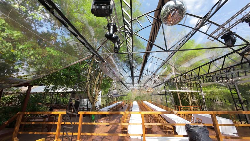 FPV drone glides through a transparent canopy wedding venue—chandeliers, banquet tables, and forest views merge in motion, revealing the spatial choreography of outdoor elegance and natural immersion.