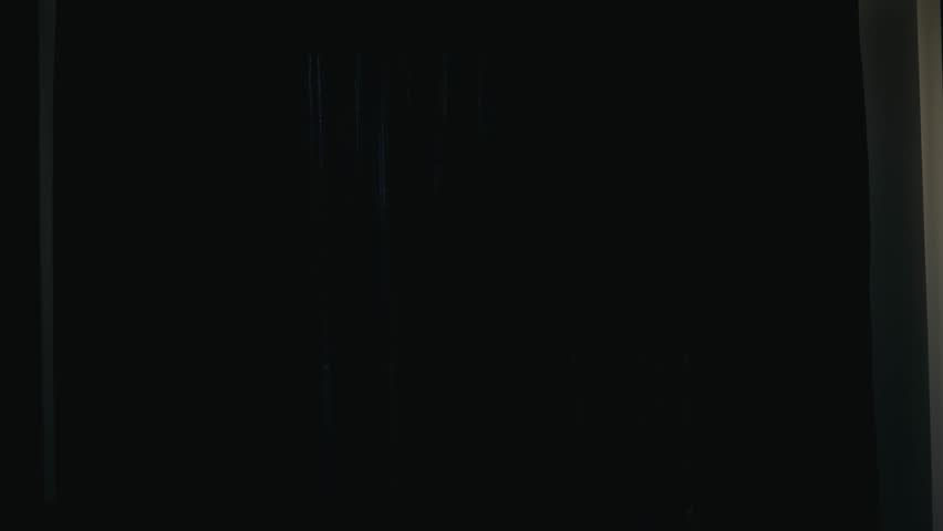 The woman pulls back the curtains and opens the morning light inside.