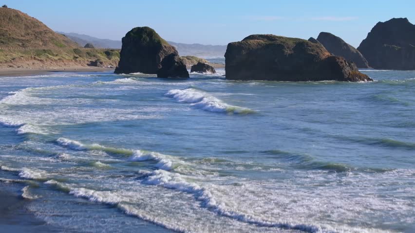 Scenic Oregon Coast beach with waves and rock formations under blue sky