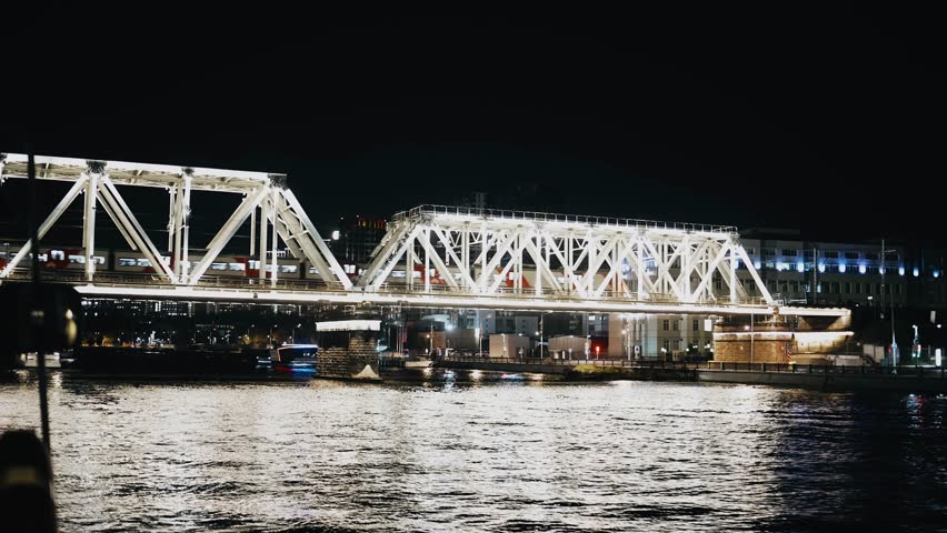 A large brightly lit bridge over a river in a night city. Cool shots in motion