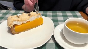 A slice of pumpkin tart with meringue topping is served with a cup of tea. The dessert is presented on a white plate, with a cup of tea on a saucer. - Powered by Shutterstock - Get 15% off with code: PIKWIZARD15