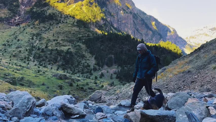 Man with Dog Crossing Stream in Autumn Mountains