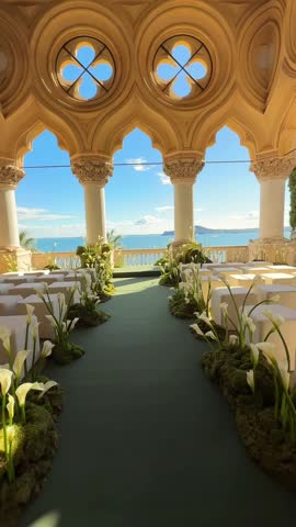 Villa terrace at Isola del Garda decorated with white lilies, green aisle, and soft white poufs for outdoor destination wedding ceremony. Elegant destination wedding setup, luxurious lakeside event
