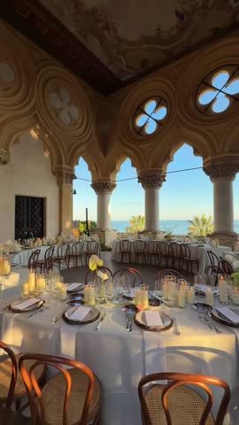 Elegant luxury wedding table decor with lilies, fine plates, glasses, white linens on historical villa terrace at Isola del Garda, Italy. Scenic wedding destination, sophisticated event planning