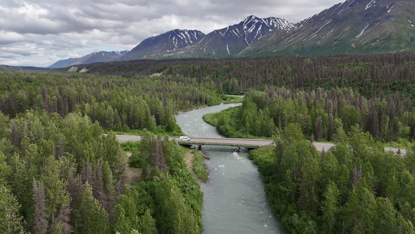 Bridge over River surrounded by trees with Tall Mountains in Background, East Fork Chulitna River, Talkeetna Mountains, late June in Alaska, Winding River with Riffles, van driving over bridge - Powered by Shutterstock - Get 15% off with code: PIKWIZARD15