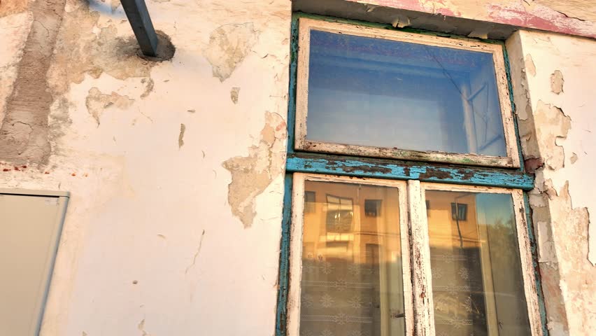 View of the worn facade of an old house. View of the old facade of the house, its windows and gates. Concept of property agencies, reconstruction in the construction business. Slow motion.