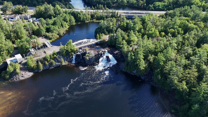 Drone orbit of High Falls in Bracebridge, Muskoka, showing the rapids, small waterfalls, surrounding forest, and the bridge over the water.