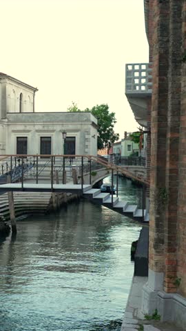 Vertical view of canal with pedestrian bridge and historic buildings Venice