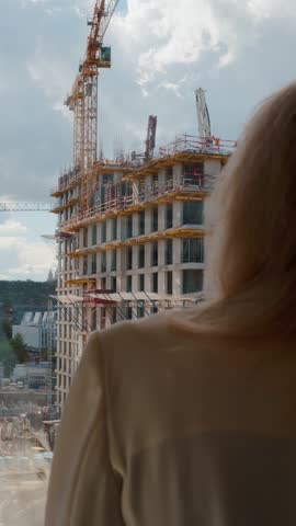 Construction of modern residential building with cranes and person in foreground