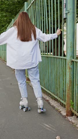 Beautiful girl with long hair rollerblading in park. Roller skating quads - popular and safe type of recreation. Vertical. High quality 4k footage