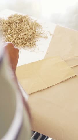 Close-up video of a person putting a sticker on a paper bag, perfect for packaging, branding, and small business themes