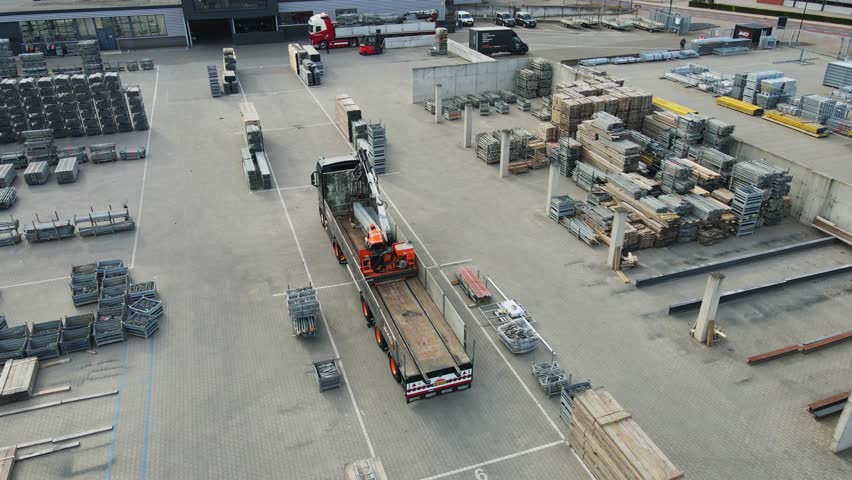 Beautiful aerial of a large truck on an industrial storage yard loading the with a onboard crane