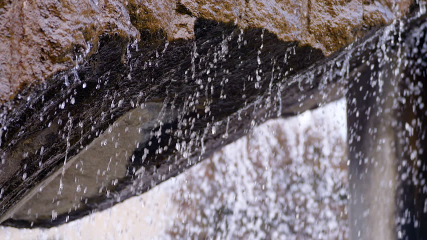 Slow motion water dripping from large rock