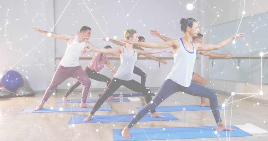Yoga group inhaling on blue mats in studio transitioning from Warrior II into Extended Side Angle. Wellness, flexibility, mindfulness, serenity, exercise, harmony, balance