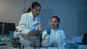 Two female scientists examining liquid in test tubes and taking notes on clipboard in modern laboratory - Powered by Shutterstock - Get 15% off with code: PIKWIZARD15
