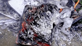 Heavily burned book or notebook with layers of ash and glowing embers. The surrounding area contains additional burned debris. - Powered by Shutterstock - Get 15% off with code: PIKWIZARD15
