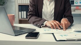 Professional businesswoman analyzing financial charts, taking detailed notes while working efficiently on laptop at modern office desk, showcasing corporate expertise and strategic planning - Powered by Shutterstock - Get 15% off with code: PIKWIZARD15