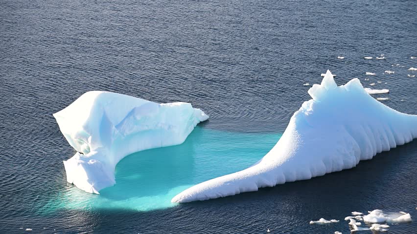 Large icebergs break the surface of calm Arctic waters under a soft sky. The stunning natural beauty showcases the unique glaciers and reflections in this serene environment.