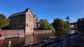 Historic warehouse with red brick facade and shutters standing beside calm canal water under blue sky in Coevorden, Drenthe. Location: Coevorden, Netherlands – Coevorden, Nederland - Powered by Shutterstock - Get 15% off with code: PIKWIZARD15