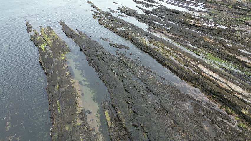 Aerial Drone Footage of the Scenic North Sea Coastline with Rocky Cove and Dramatic Coastal Formations Beside the Historic St Andrews Castle Ruins in Scotland, Showcasing Rugged Clifftops, Ocean Waves