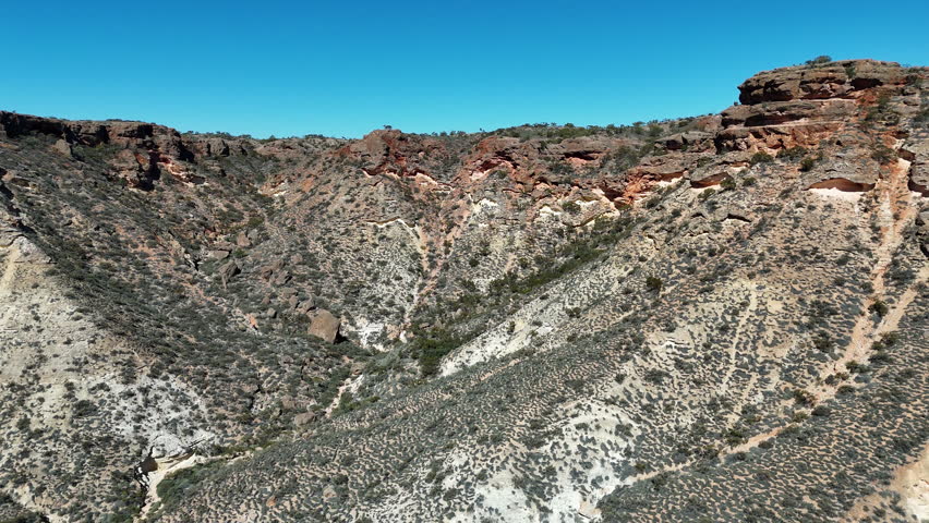 aerial drone shot of an offroad vehicle driving along charles knife canyon with iconic red rock formations in the desert like area near Exmouth in West Australia.