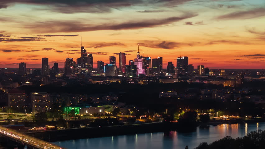 Aerial panorama Warsaw city with night illumination. Drone time-lapse cityscape downtown silhouettes skyscrapers modern architecture buildings on horizon, sunset sky, evening cityscape top view