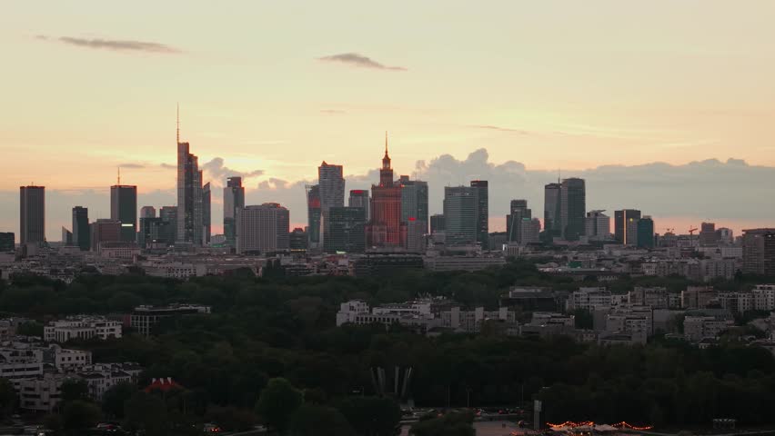 Aerial panorama of Warsaw city during golden hour at sunset. Cinematic drone shot of cityscape downtown silhouettes of skyscrapers modern architecture buildings on horizon in evening