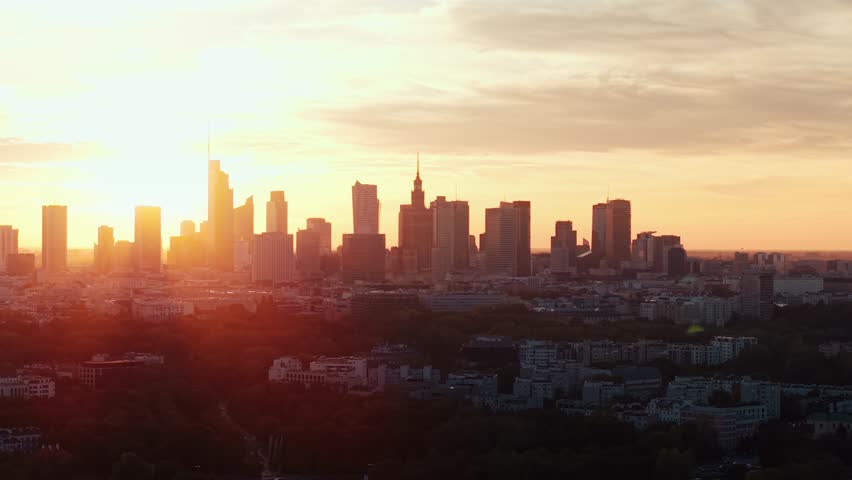 Aerial panorama of Warsaw city during golden hour at sunset. Drone shot cityscape downtown silhouettes of skyscrapers modern architecture buildings on horizon, orange sunlight rays