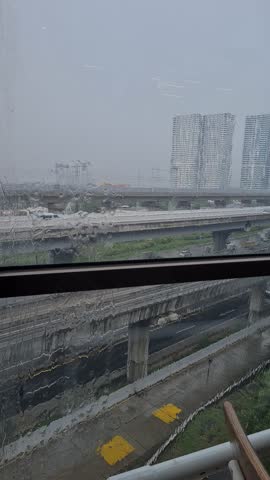 Large glass window with heavy rain, city view blurred by water drops flowing on glass during storm.