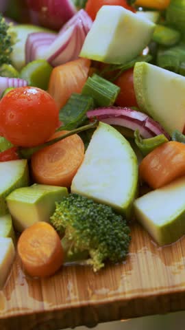 Cook is putting sliced vegetables into the bowl, making fresh vegetarian salad for healthy nutrition
