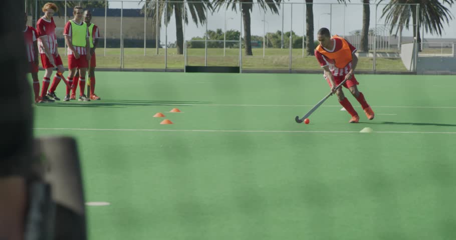 Whistle blowing athlete slaloming cones in hockey, camera operator adjusting nodes intensifying. Athletic, sportsmanship, training, teamwork, dynamic, outdoor, vibrant